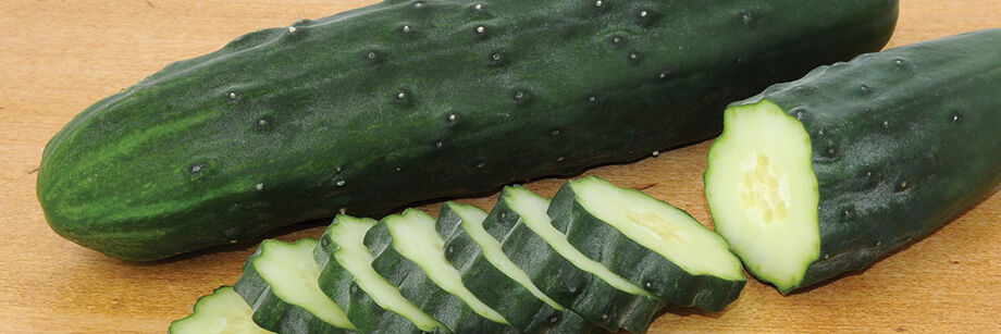 Two cucumbers on a cutting board, one sliced.