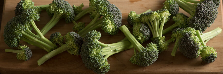 Broccoli florets, laid out on a wooden cutting board.