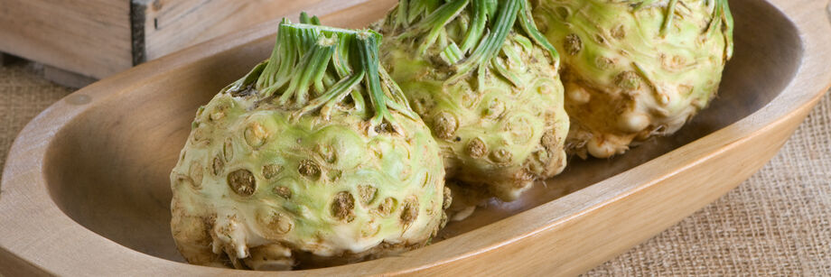 Three celeriac roots in a wooden dish.