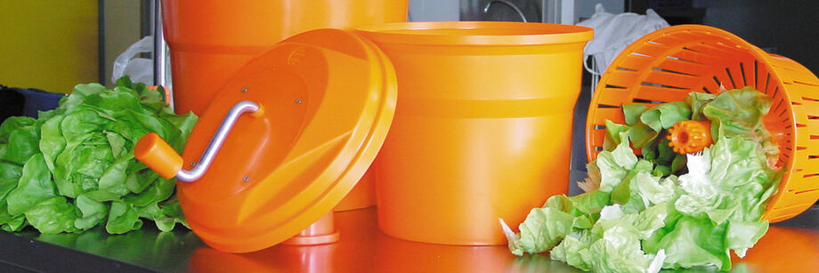 Two salad spinners on a counter alongside freshly washed and spun lettuce.