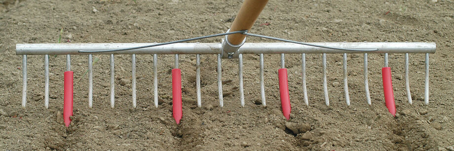Plastic row markers attached to a bed preparation rake are being used to mark rows before planting.