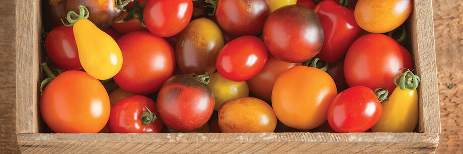 An assortment of small and colorful specialty tomatoes on display in a wooden box.