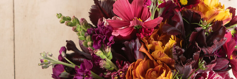 A bouquet of flowers in shades of burgundy, copper, and rose.