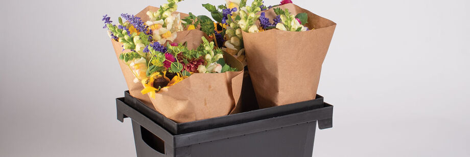 Four flower bouquets in a black plastic Procona Florida container.