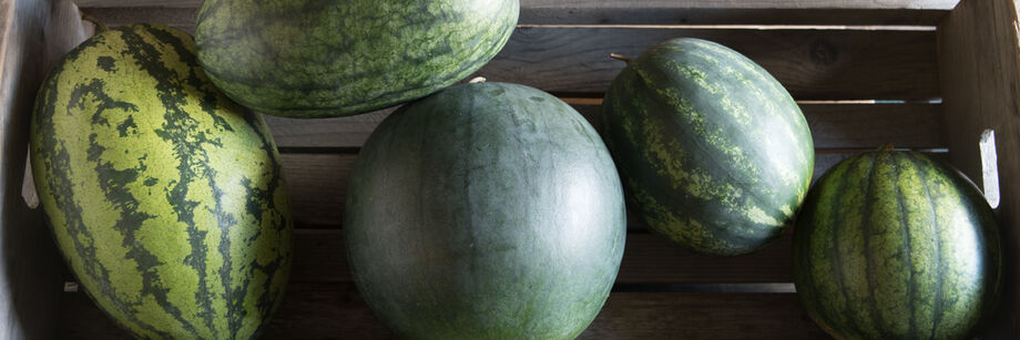 Several watermelons in a wooden crate.