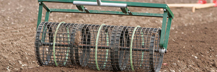 A seedbed roller being used to firm and smooth a seedbed prior to planting.