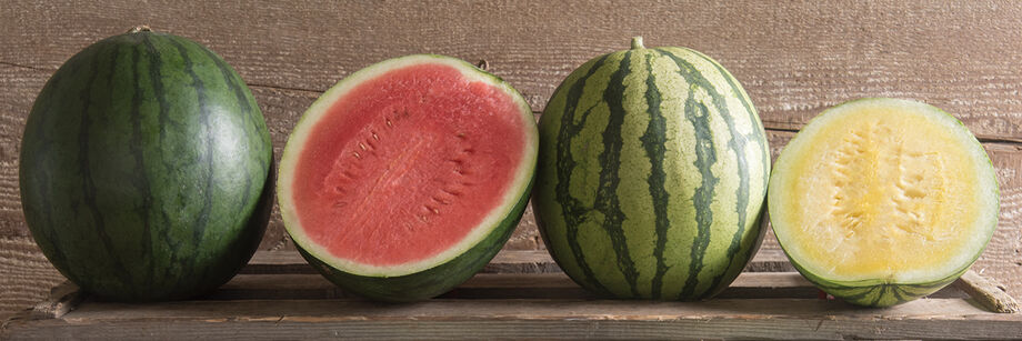 Four watermelons in a row, with two cut open to reveal the flesh.