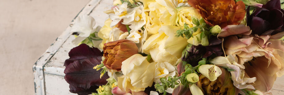 A bouquet of flowers in warm neutral colors such as cream, copper, burgundy, and pale lavender.