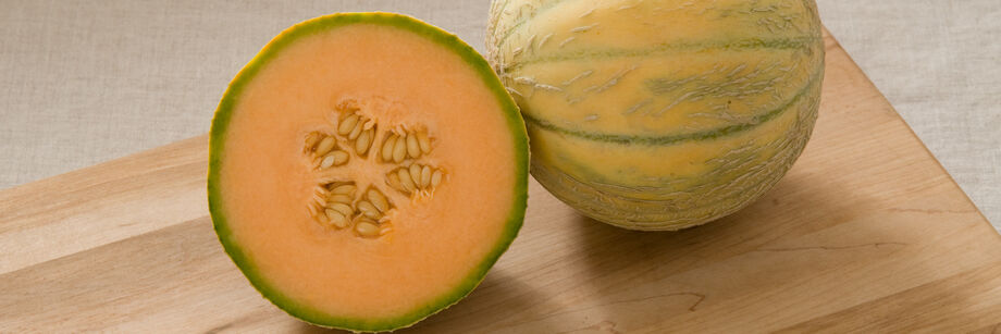Two round French melons. One is shown whole and one is cut open to show the orange flesh.