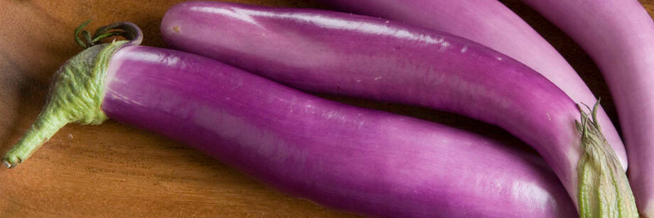 Several oblong, pale-purple Asian eggplants laid out on a table.