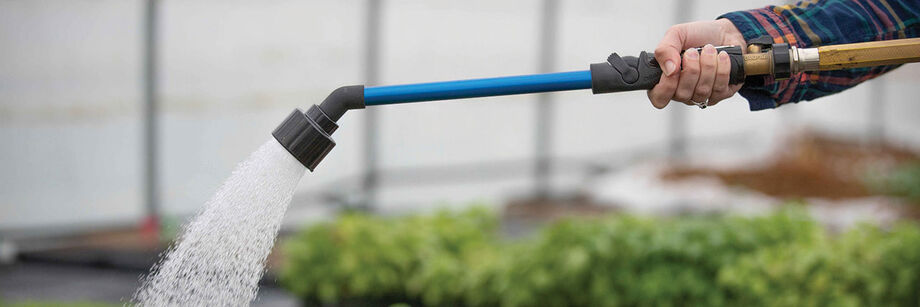 Person watering by hand with a rain wand.