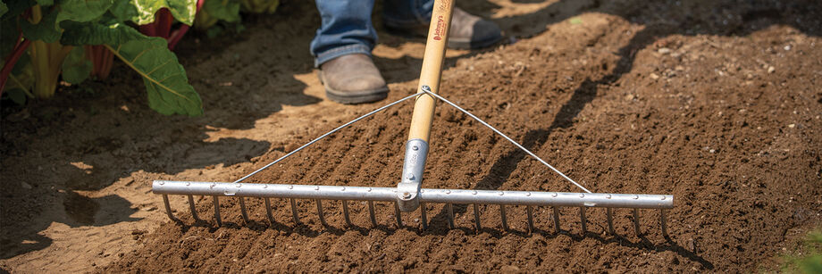 Person using an electric tiller to shape the seedbed prior to planting.