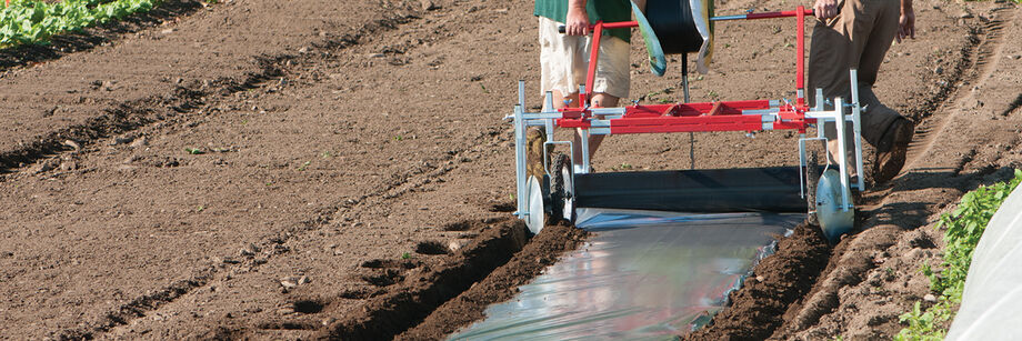 Two people using the manual mulch layer.