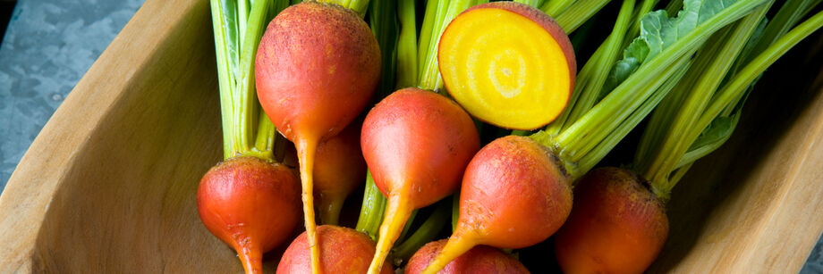 Round golden beets in a wooden bowl.