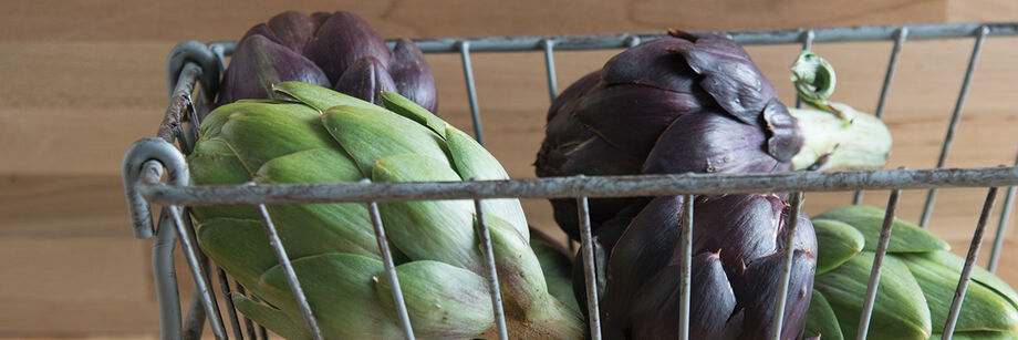 Metal basket holding green and purple artichokes grown from artichoke seeds offered by Johnny's.