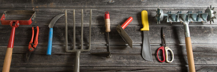 A selection of Johnny's garden hand tools laid out on a barn floor.