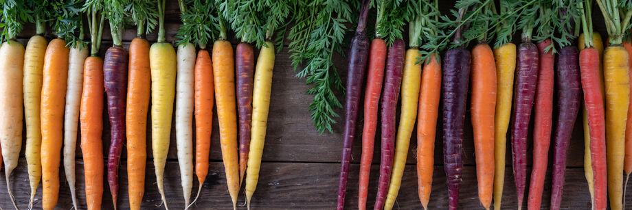 An array of colored carrots laid out on a wooden table.