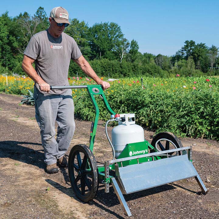 Johnny's flame weeder being used in a prepped bed