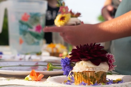 Children decorating cupcakes with edible flowers at a birthday party