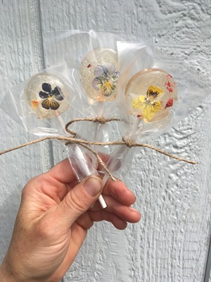 Three lollipops with edible flowers in them