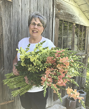 Lisa with an armful of antirrhinum, next to her flower shed